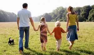  family holding hands and walking away from camera in meadow