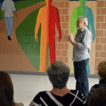 Photo of artist speaking to audience gathered in Decker Lake facility