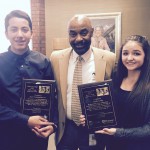 Photo of two students holding award plaques next to West Lake principal