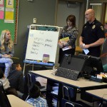 Photo of police officer presenting new book to Wilson Elementary students