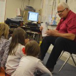 Photo of volunteer reading book to Moss Elementary students