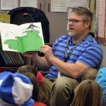 Photo of administrator reading book to Moss Elementary students