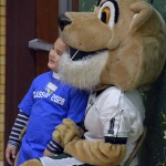 Photo of kindergarten student posing for photo with Kearns High mascot