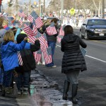 Photo of students standing on sidewalk holding U.S. flags
