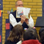 Photo of administrator reading book to Moss Elementary students