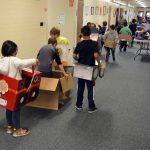 Orchard Elementary students line up in hallway with cardboard cars