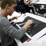 Student drawing on black paper