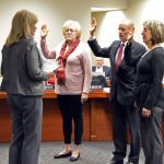 Three board members reciting the oath of office during board meeting