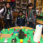 Three students stand behind model prototype city