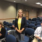 Carrie Johnson stands at board meeting