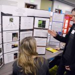 Student presenting science fair project to teacher