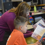 Elementary teacher reads aloud with student