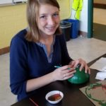 Evergreen student painting Christmas tree ornament