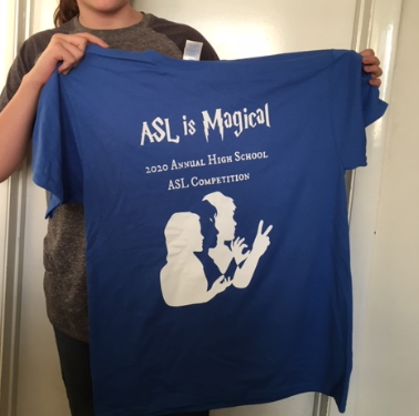 Student holding ASL competition t-shirt