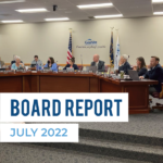 Board members listen to presentation. Text: Board Report July 2022